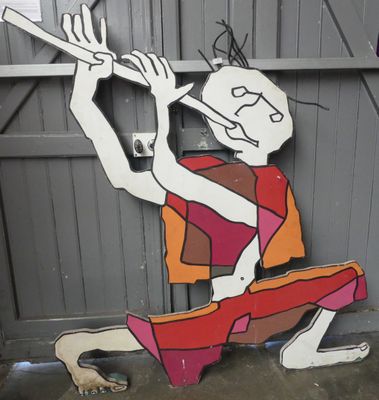 un tableau représentant un homme jouant de la flûte sur la façade d'un immeuble
