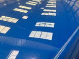 a reflection of a building on the top of a blue car