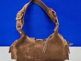 a brown sued purse with a leather handle on a blue background