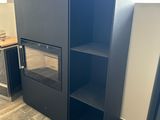 une armoire noire dans un coin d'une pièce où se trouve un poêle