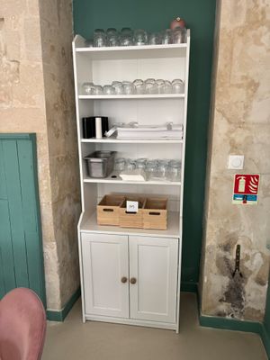 une armoire blanche sur laquelle sont posés des objets en verre, dans un coin de la pièce