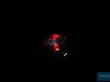 the red ball is lit up in the dark by the light of a flashlight