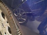 a close up of a blue car with a broken tire