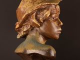 bronze bust of a woman with a hat on a wooden table