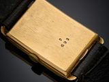 a close up of a gold plated wrist watch with a black strap