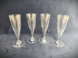 four champagne glasses are lined up on a black background