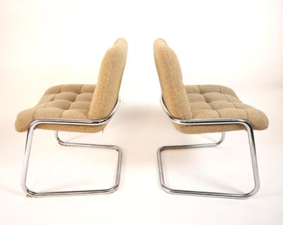 pair of chrome and upholstered lounge chairs with beige upholstered cushions
