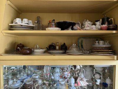 de nombreuses assiettes et tasses sur les étagères de ce placard