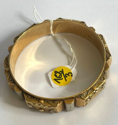 a gold bracelet with a tag on it on a white surface