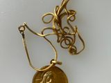 collier composé d'une pièce d'or posée sur un fond blanc et entourée d'une chaîne