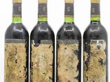 four bottles of wine are lined up in a row on a white surface