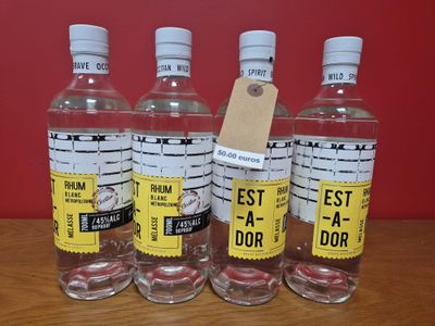 quatre bouteilles d'eau posées sur une table en bois près d'un mur rouge