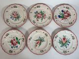 six assiettes ornées de motifs floraux posées sur une surface blanche