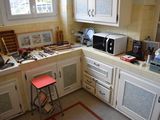 a kitchen with a microwave, microwave oven, and a stool in it