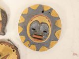 three wooden masks hanging on a wall next to each other