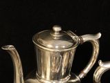 a silver tea set on a table with a black background