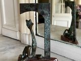 a statue of a cat sitting on a table in front of a mirror