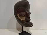 an image of a wooden mask on a stand on a white surface