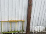 a yellow bench sitting next to a metal fence