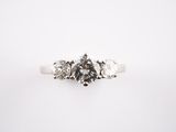 a close up of a three stone diamond ring on a white background