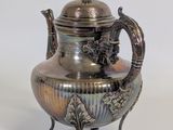 a silver tea pot on a stand on a white background