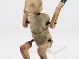 figurine en bois représentant un homme tenant une batte de baseball, posée sur un socle transparent