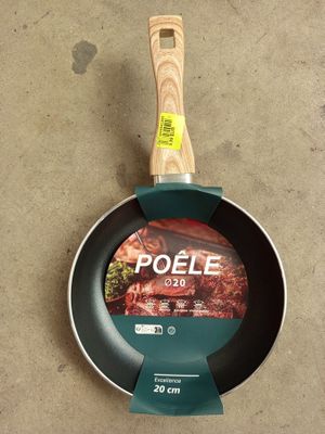 une poêle avec un manche en bois posée par terre