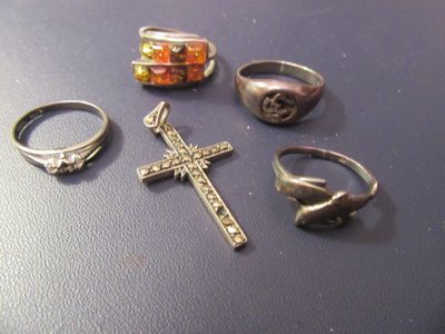 cinq bagues différentes et une croix posées sur une table