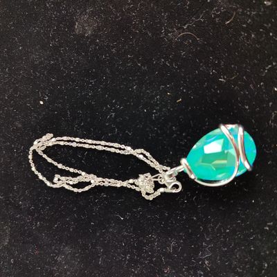 a close up of a necklace on a black surface with a silver chain