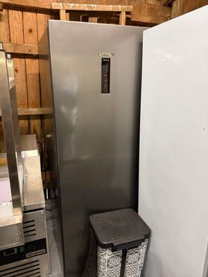 a silver refrigerator and a black trash can in a room