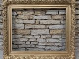 an old picture frame on a stone wall with a stone wall in the background