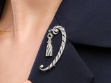a close up of a woman ' s hand holding a silver broochet