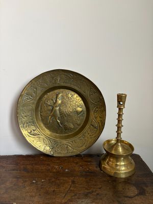 une assiette en or et un bougeoir en laiton posés sur une table en bois