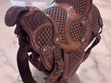 a brown leather saddle sitting on a marble table