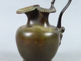 un vase en bronze muni d'une anse, sur fond blanc