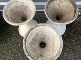 three cement vases sitting next to each other on the ground