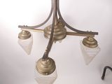 a chandelier with three glass shades hanging from the ceiling