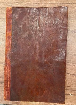 un vieux livre en cuir marron posé sur une table en bois