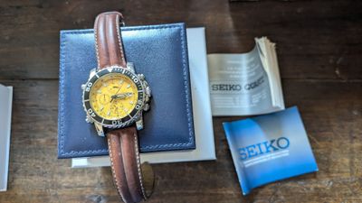 une montre posée sur un portefeuille, à côté d'un livre
