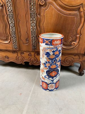 un grand vase posé par terre à côté d'un meuble