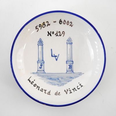une assiette bleue et blanche sur laquelle est représenté un phare
