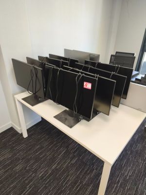 four computer monitors on a white desk in an office