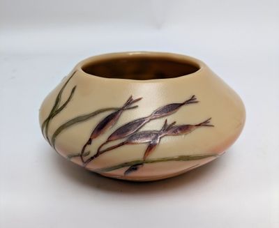 a small vase with fish on it on a white surface