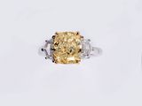 a yellow diamond and diamond ring on a white surface