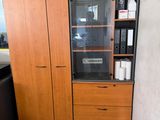 a wooden cabinet with a glass door in the corner of a room