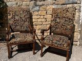 two chairs sitting next to each other in front of a brick wall