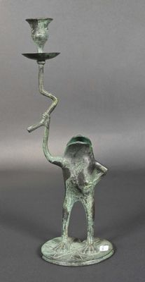 a statue of a frog holding a candle on a stand
