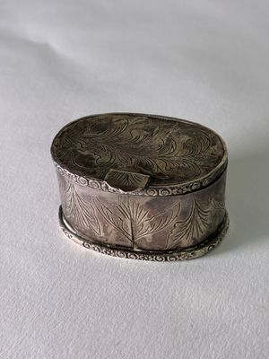 une boîte argentée posée sur une surface blanche