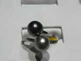 une bague ornée de deux perles noires, exposée dans une vitrine