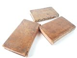 three old books sitting on top of each other on a white surface